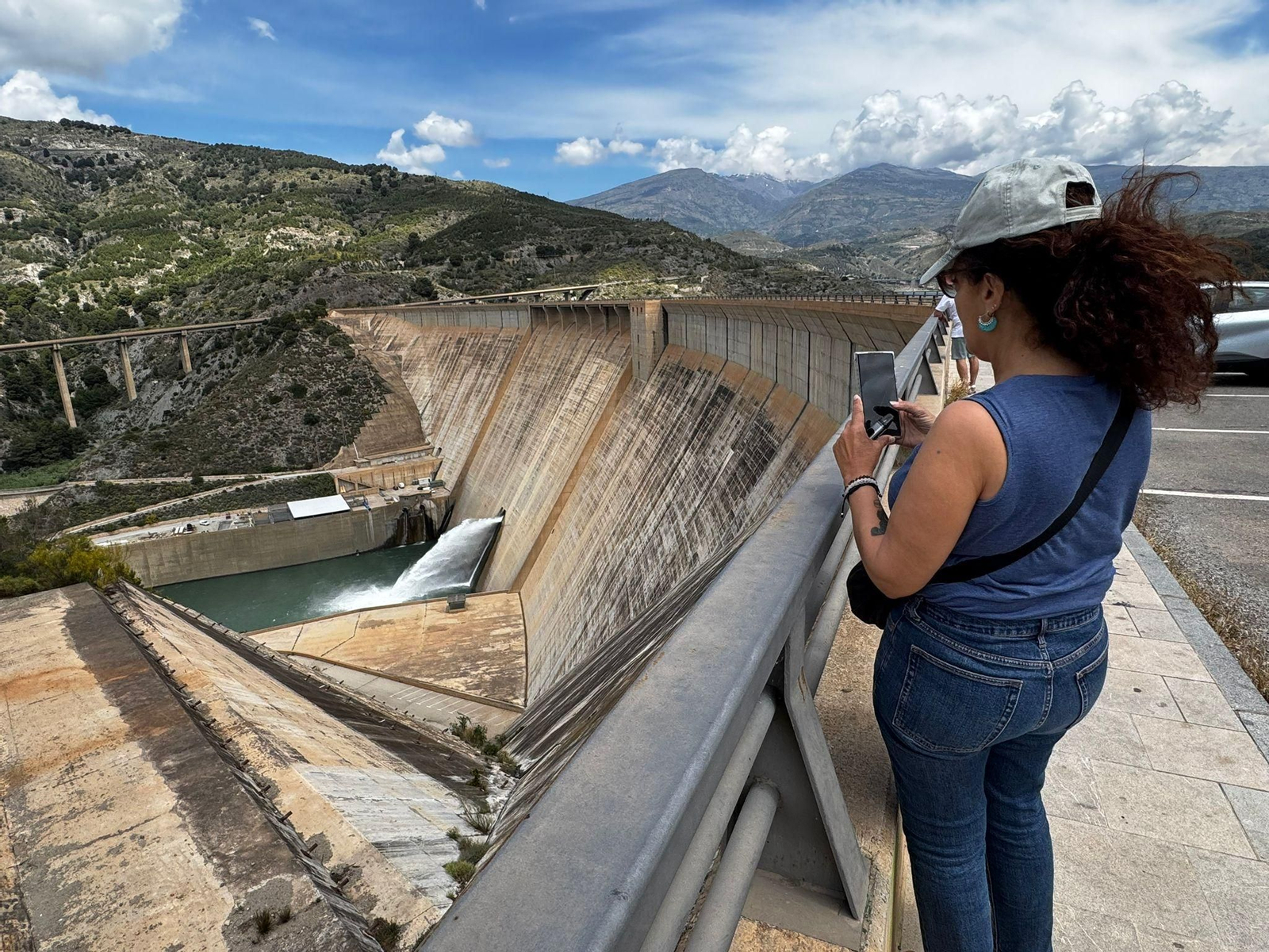 Una mujer hace una foto de la Presa desembalsando agua