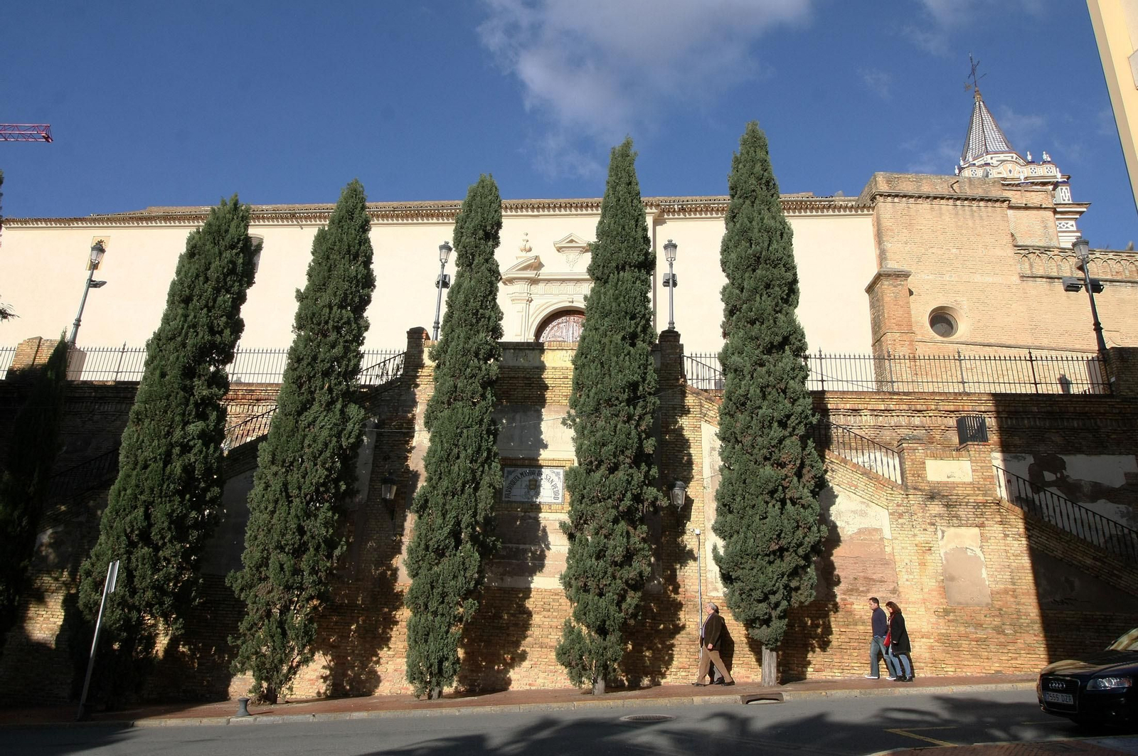 La hilera de cipreses que apuntala el muro y la propia iglesia en su visión desde el paseo de Santa Fe. La hilera de cipreses que apuntala el muro y la propia iglesia en su visión desde el paseo de Santa Fe.
