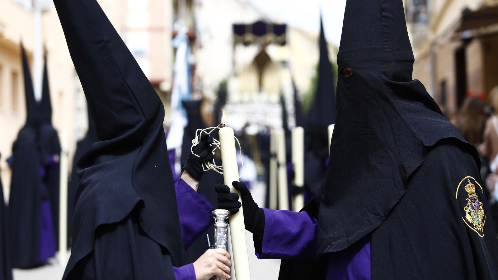 Nazarenos prenden una vela con María Santísima del Mayor Dolor en su Soledad al fondo.