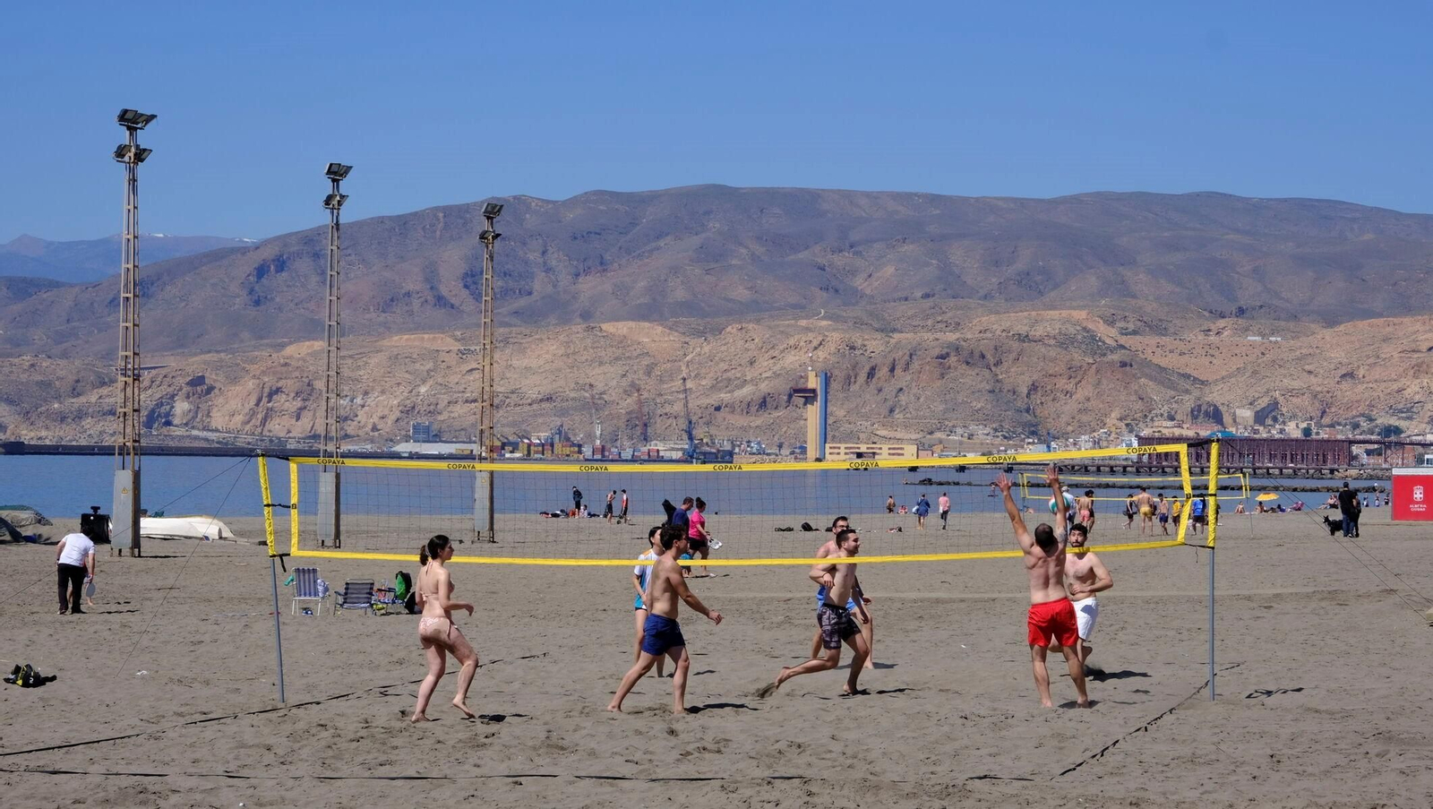 Un grupo de personas juegan al vóley playa en la playa de El Zapillo durante una mañana de verano.