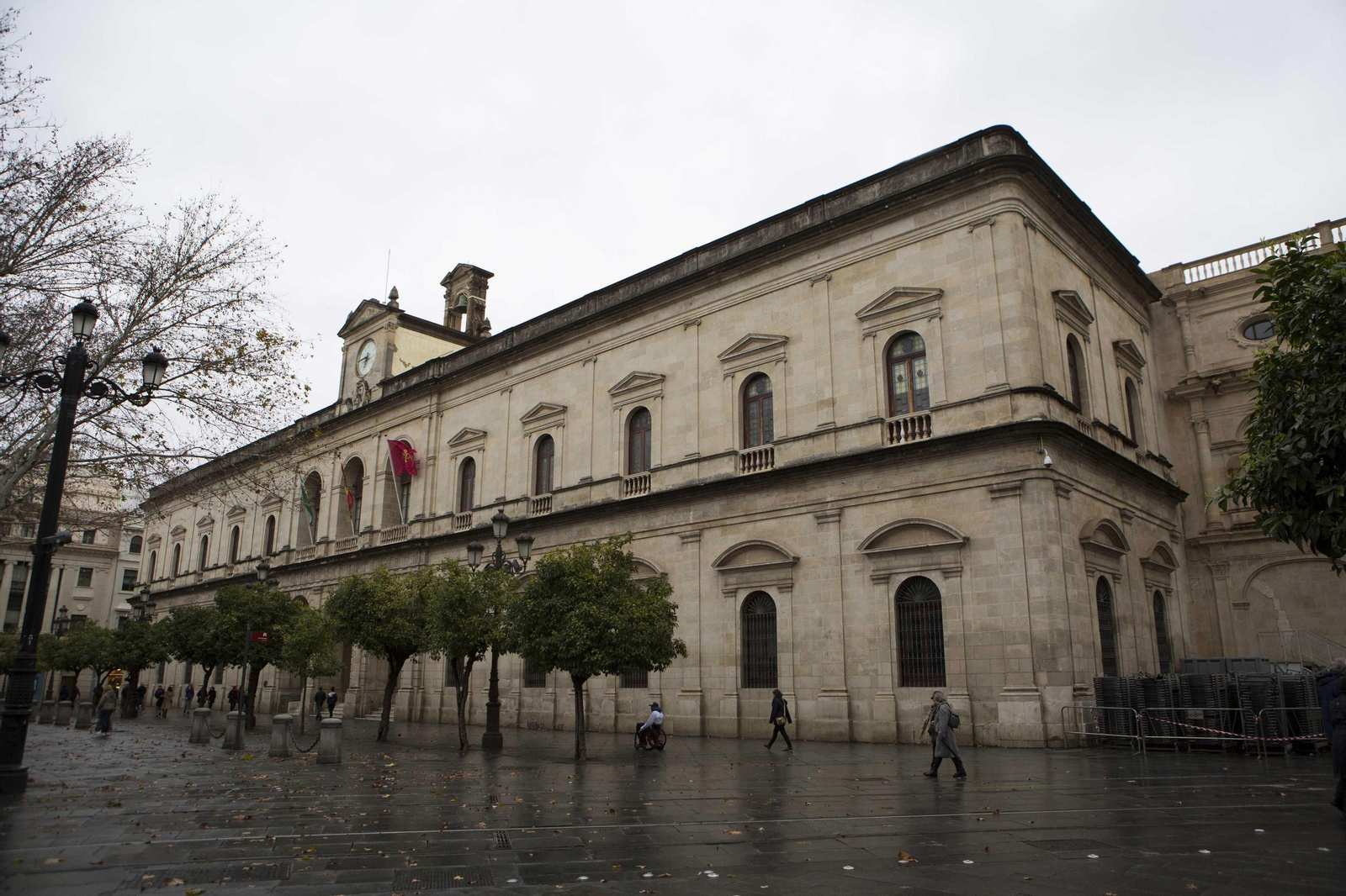 Varias personas caminan cerca de la fachada principal de la Casa Consistorial.