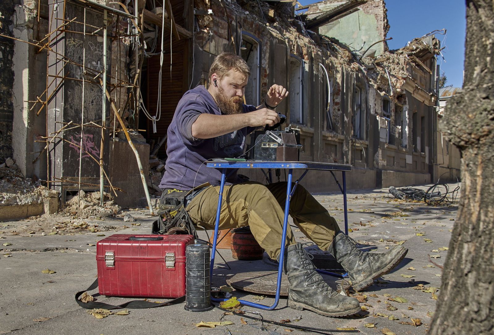 Un especialista intenta reparar la fibra óptica ante un edificio administrativo destruido en Jarkov.
