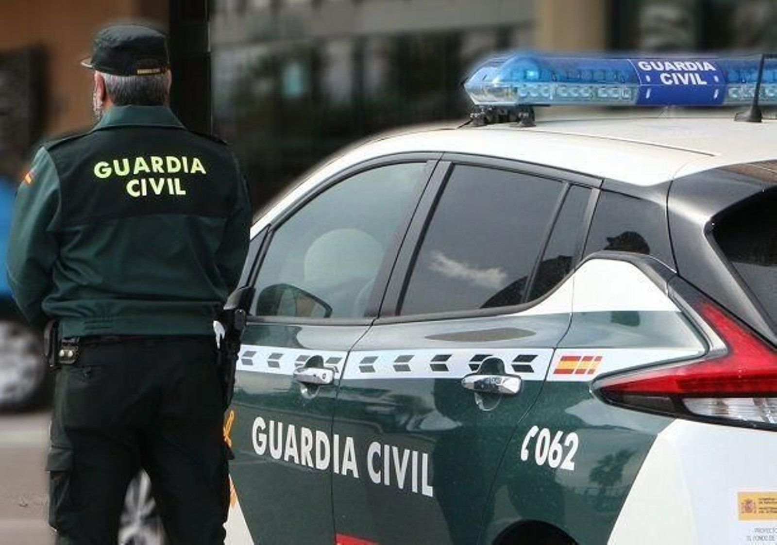 Un agente de la Guardia Civil, junto a un coche patrulla.