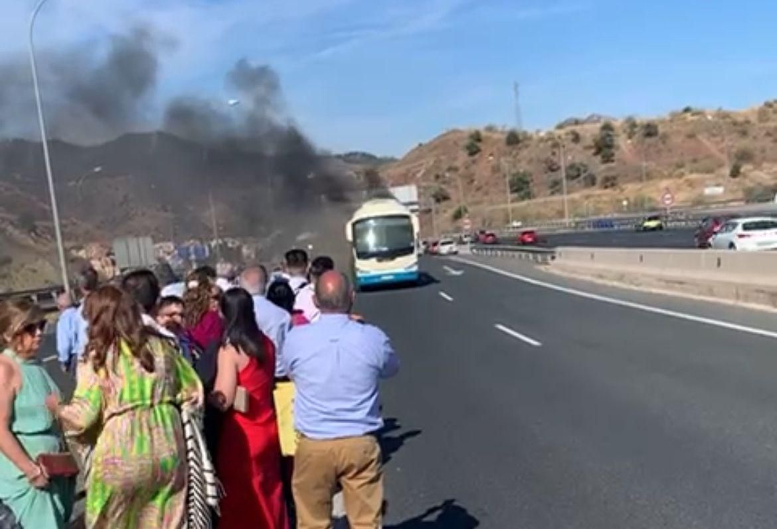 Los pasajeros, ya fuera del autobús, contemplan como arde en la carrretera en Málaga.