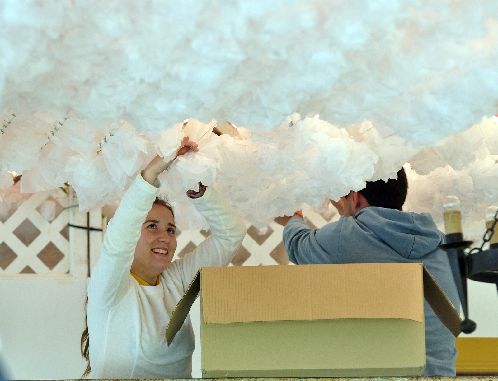 Dos trabajadores colocan flores de papel en una caseta.