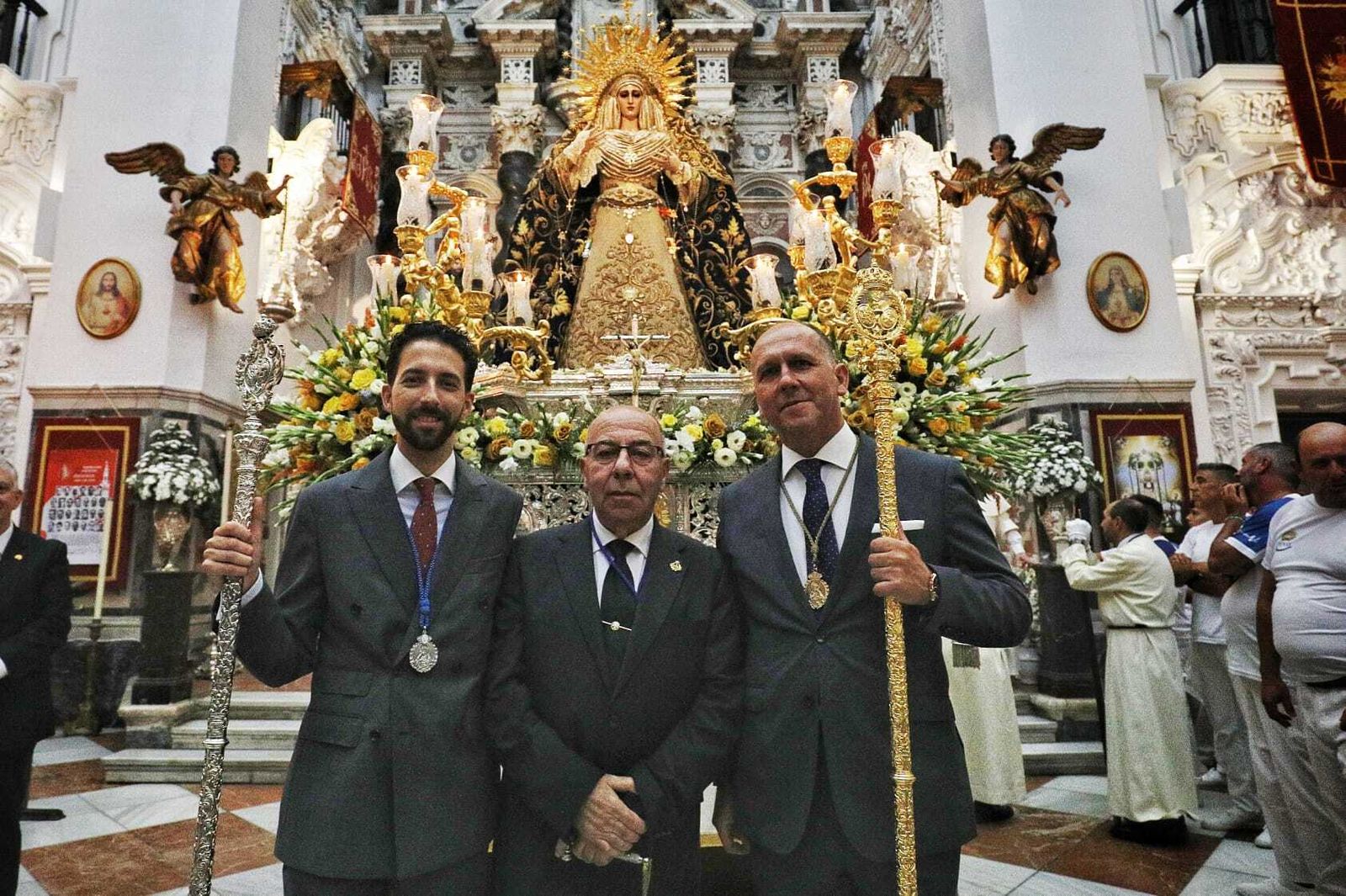 El hermano mayor y el mayordomo de La Palma flanquean al capataz de la Virgen de las Penas.