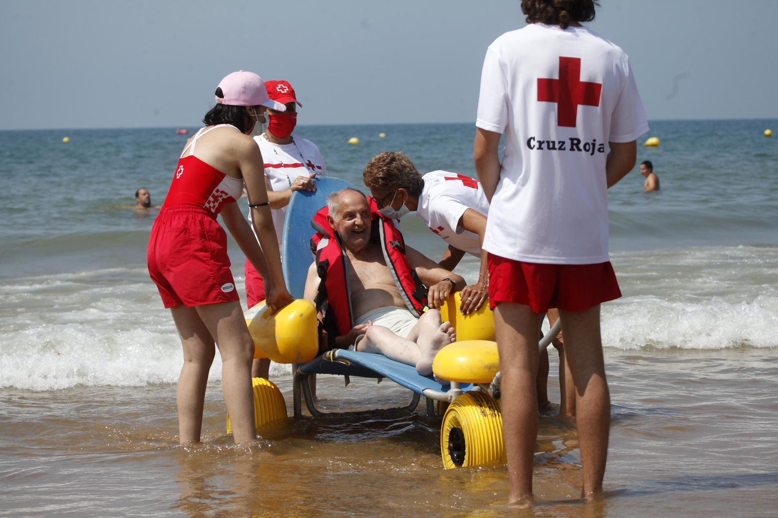 Uno de los usuarios del programa es ayudado a bañarse en la playa por voluntarios de Cruz Roja