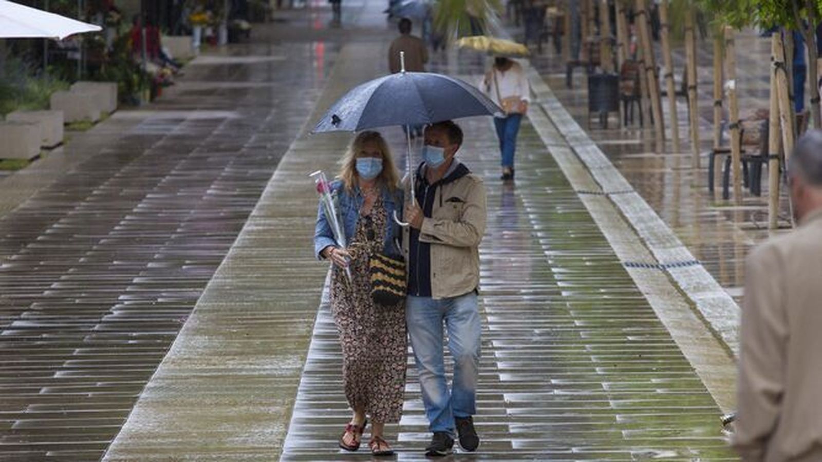 Una pareja camina bajo la lluvia por la Alameda Principal de Málaga.