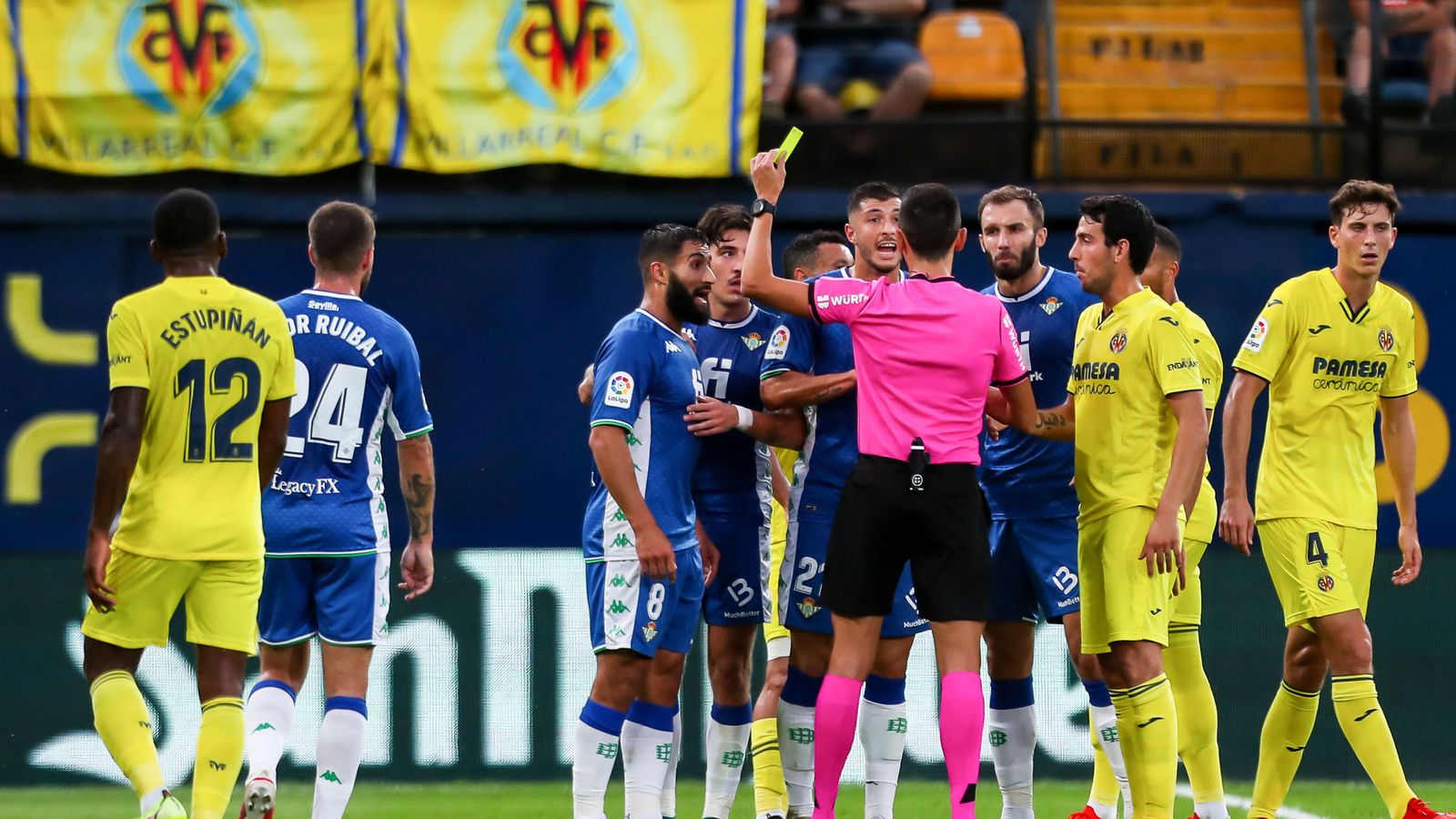 Sánchez Martínez le muestra la tarjeta amarilla a Fekir por un golpe a Capoue.