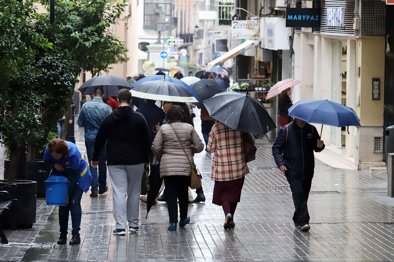 Varias personas pasean por el centro de Huelva durante un día de lluvia.