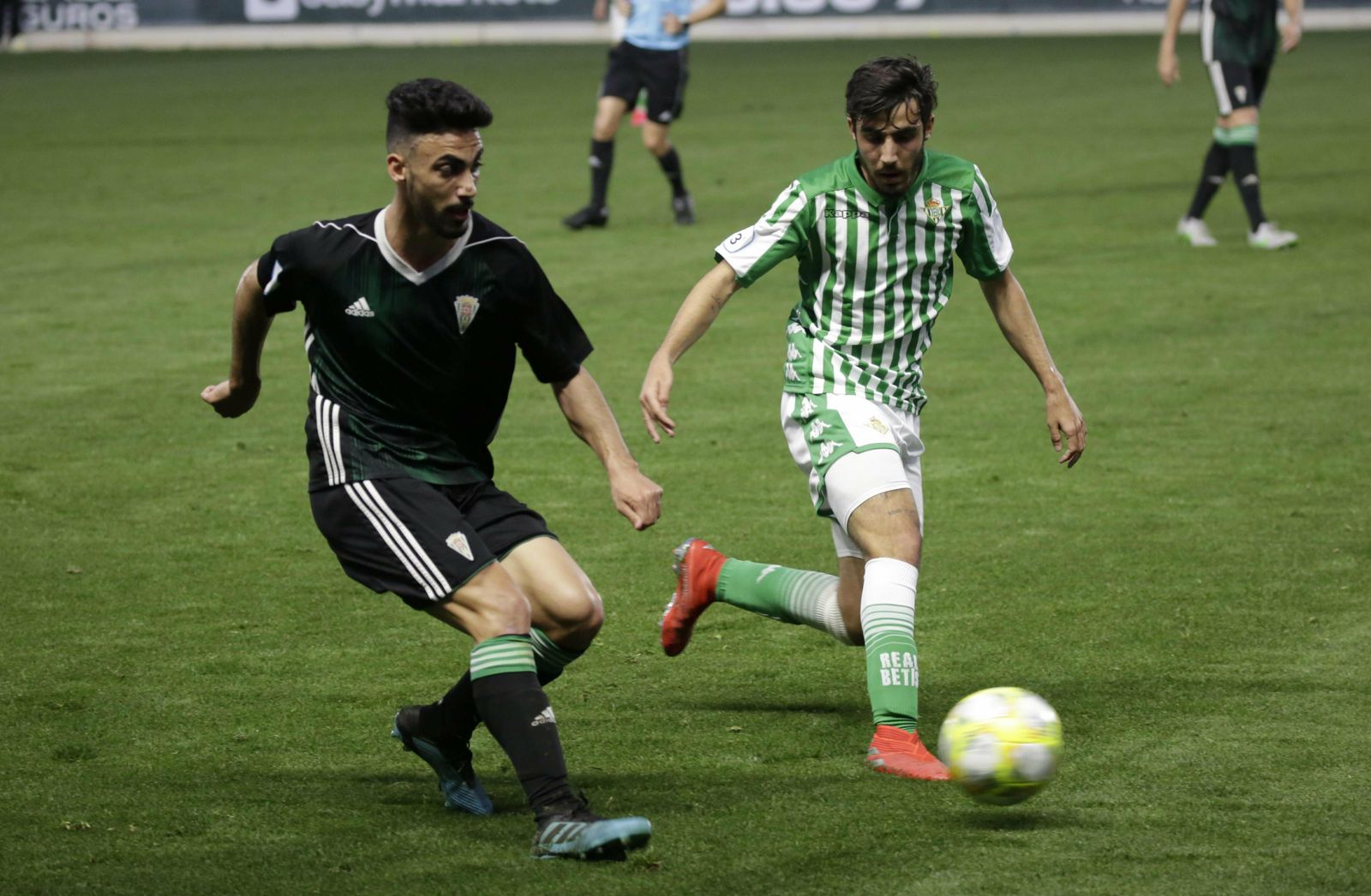 El cordobesista Moyano toca el balón ante la presencia de un jugador bético.