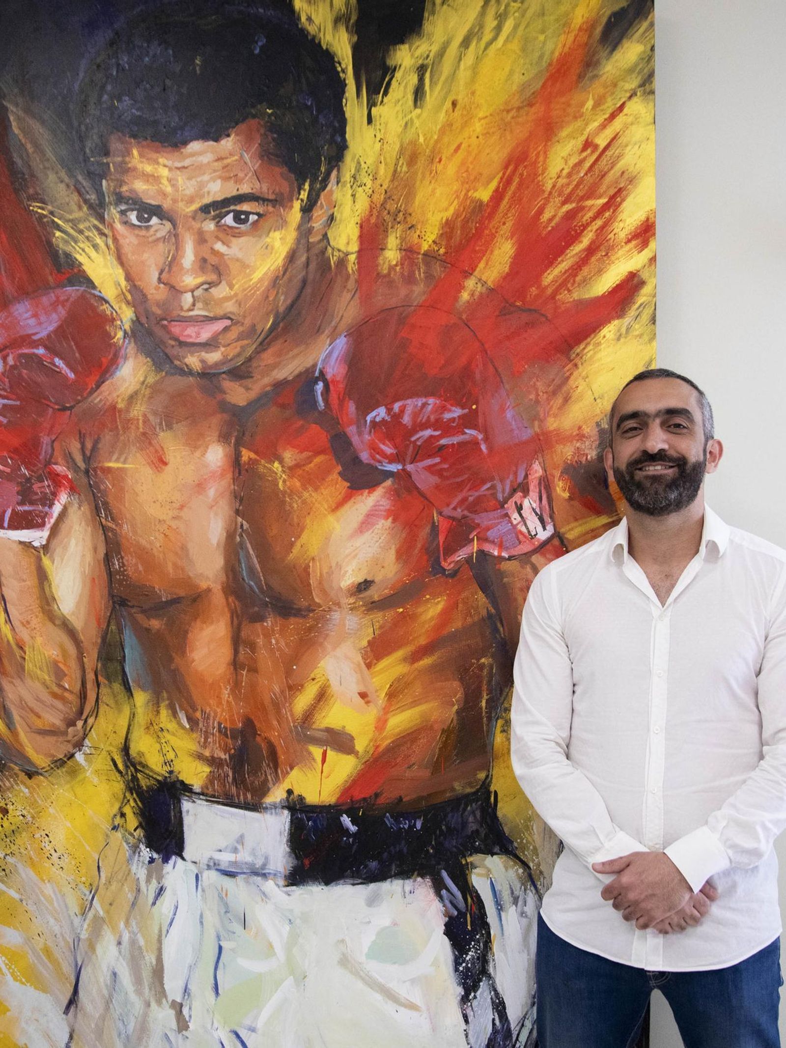 El Assy, que confiesa haber sido campeón escolar de boxeo, junto a un retrato del legendario Mohamed Ali