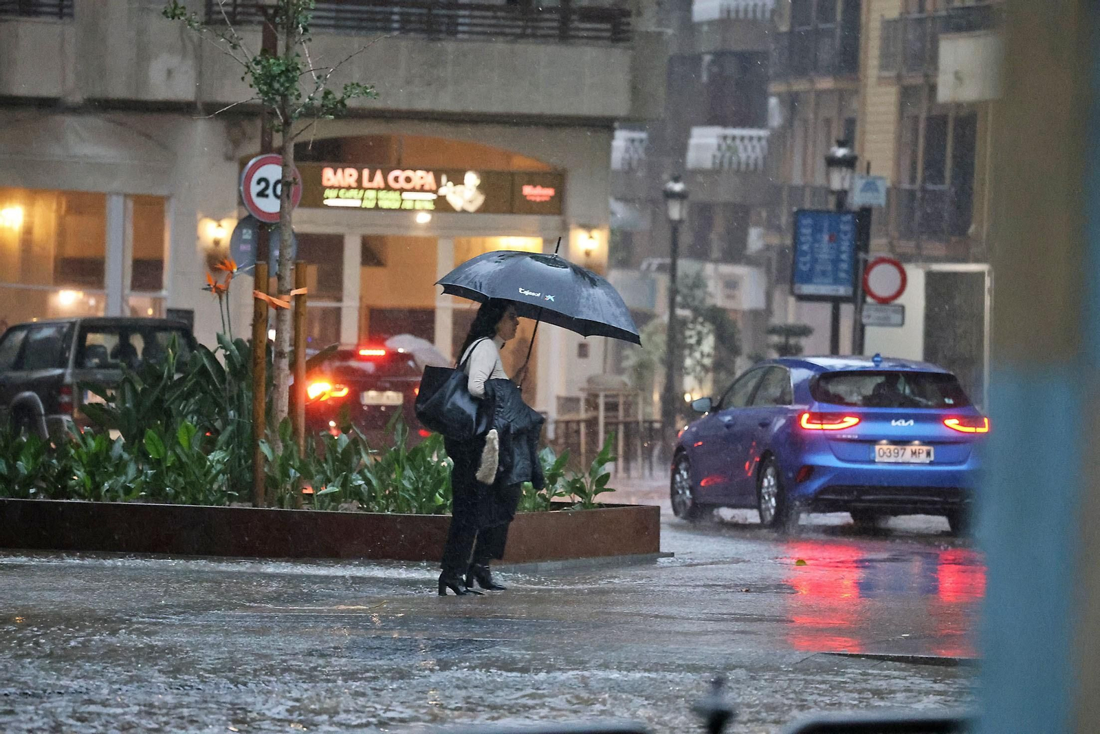 Una mujer se refugia de la lluvia con un paraguas.