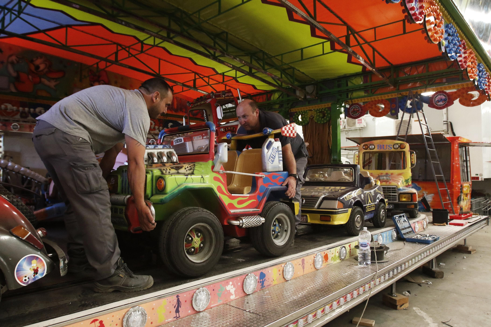 Unos feriantes desmontan una atracción en una nave de Lucena.