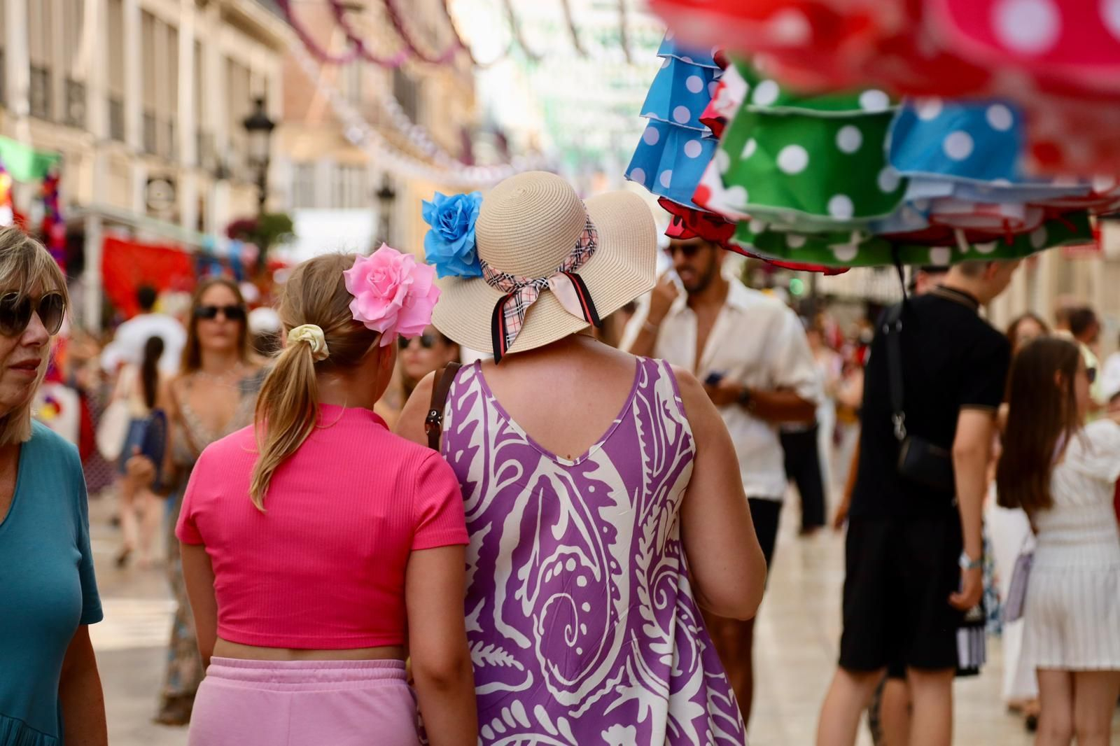 Una mujer se protege del calor con un sombrero en el Centro durante la Feria de Málaga.