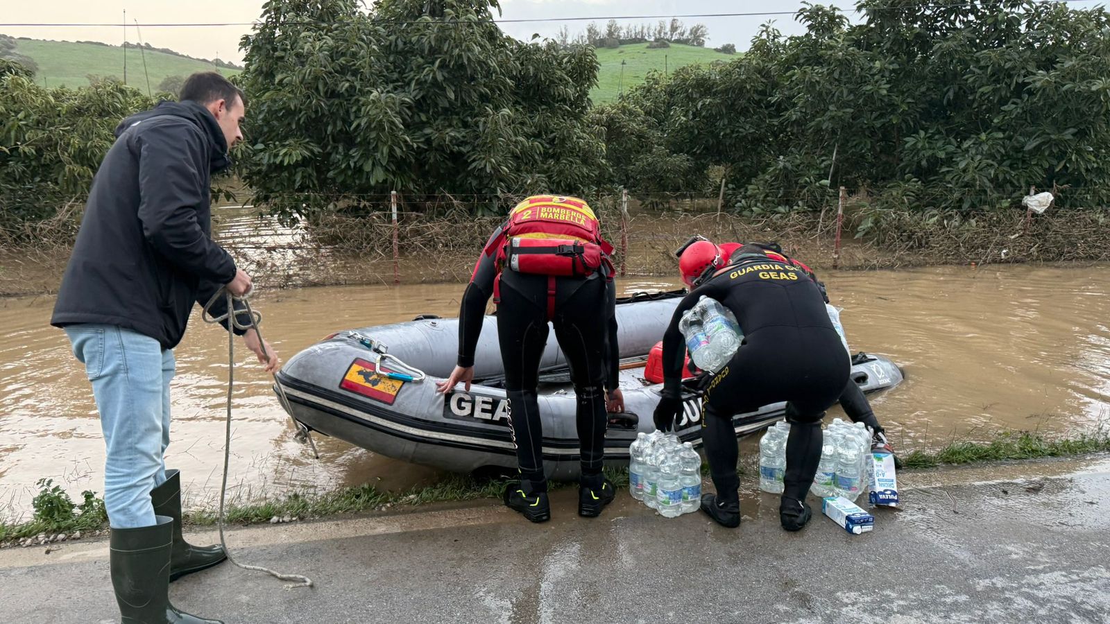 Bomberos y Guardia Civil trasladando víveres en zodiacs.