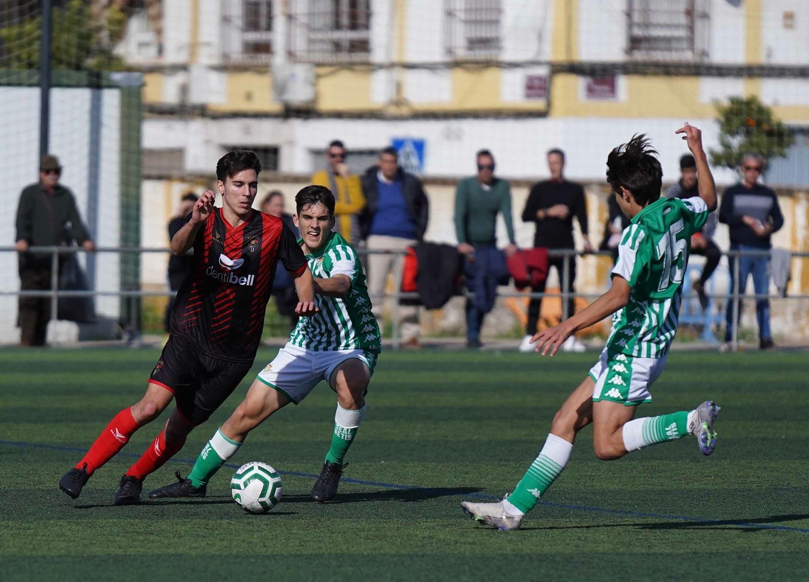 Un jugador del Séneca trata de salir con el balón controlado entre dos futbolistas béticos.