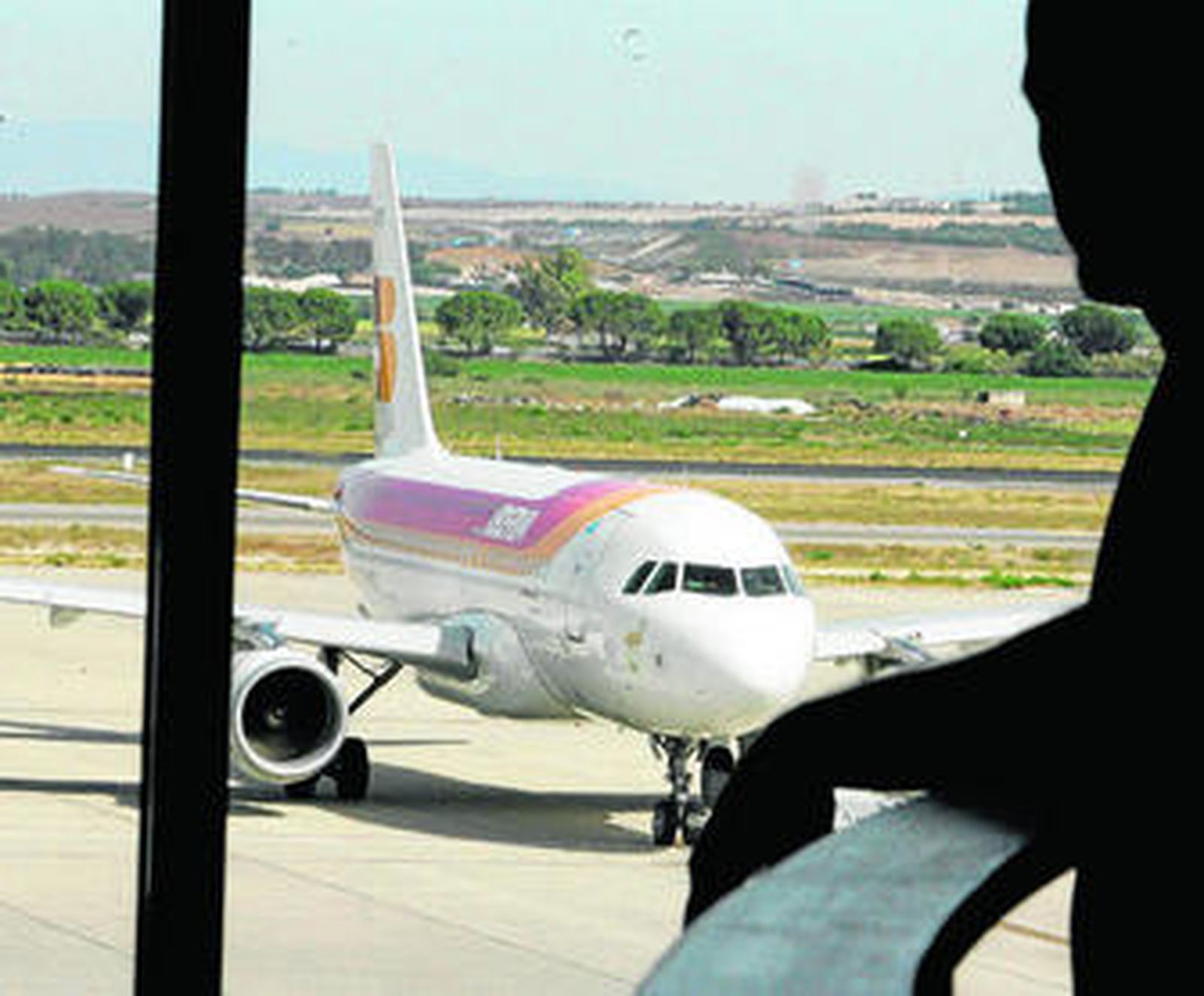 Una persona contempla desde la cafetería un avión de Iberia en el aeropuerto el pasado mes de febrero.