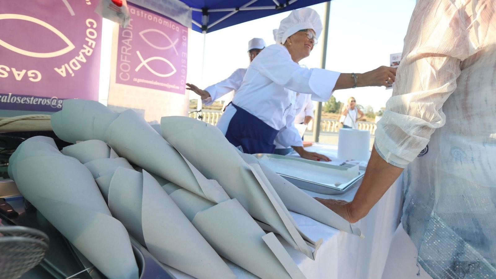 La cofradía gastronómica Los Esteros repartiendo tortillitas de camarones en un evento.