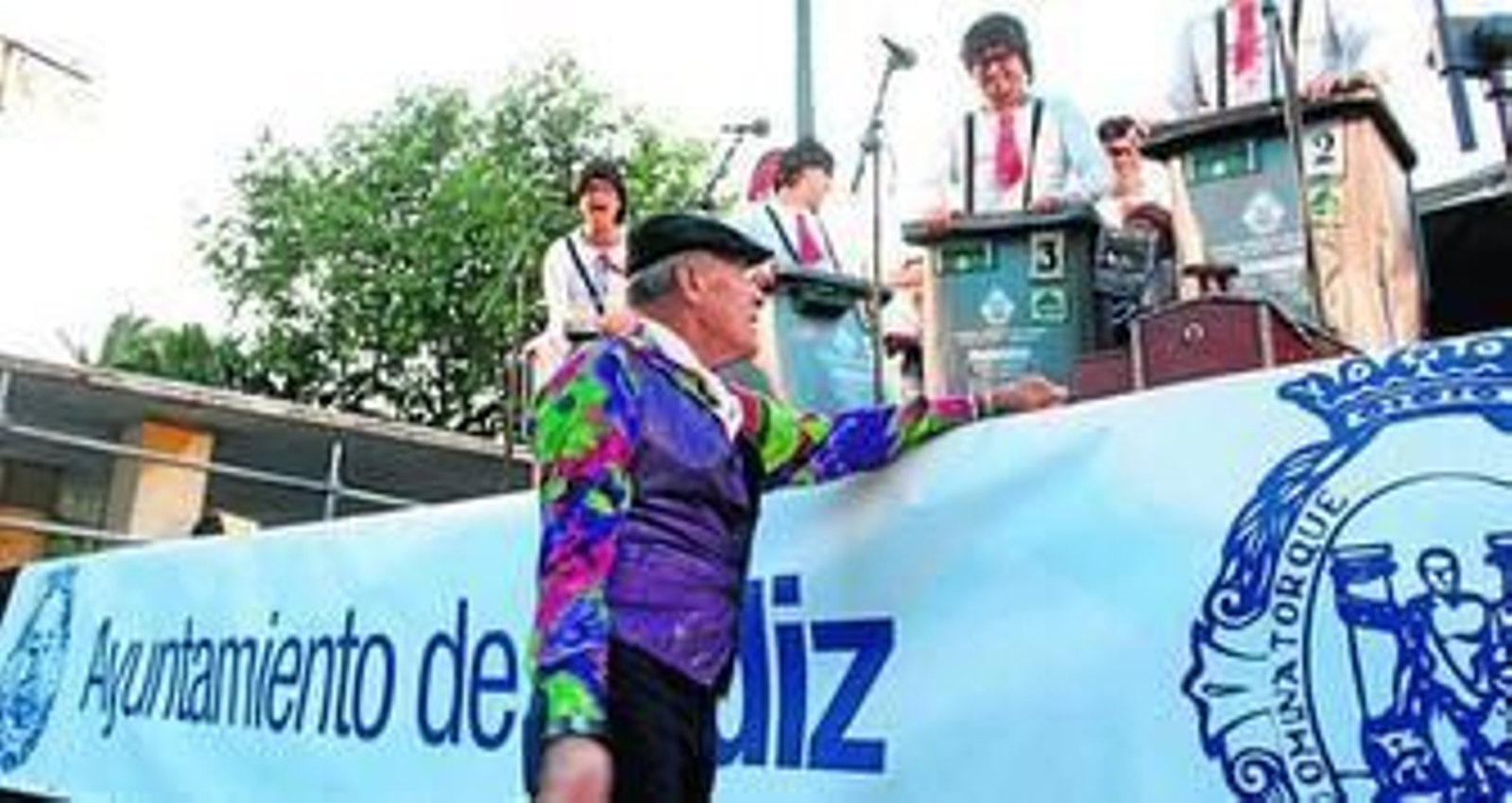 José Payán 'El Pillo', con el tipo de 'Al compás de mi cepillo', saluda a la chirigota 'Los recortaos' a pie de escenario.