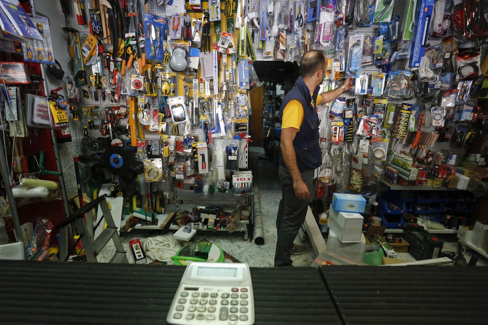 Un autónomo  coge uno de los productos de su ferretería.