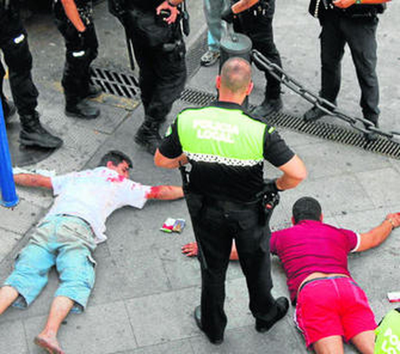 Los dos hombres, tendidos en el suelo y rodeados por los policías.