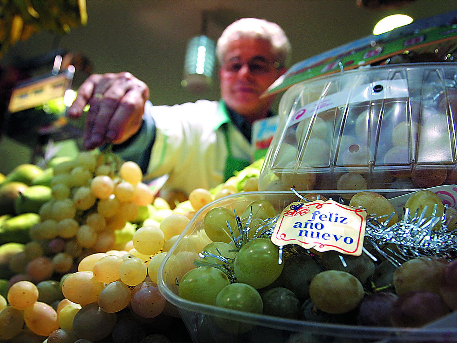 Un frutero muestra varios ramos de uvas