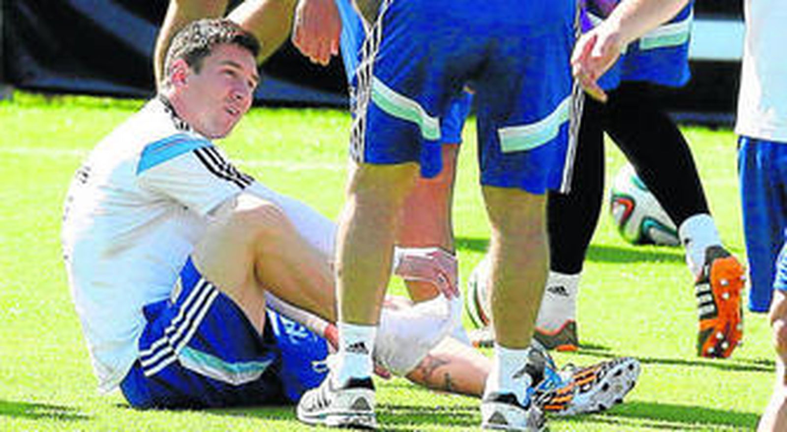Lionel Messi se quita una de sus zapatillas durante un entrenamiento ante la mirada de algunos compañeros.