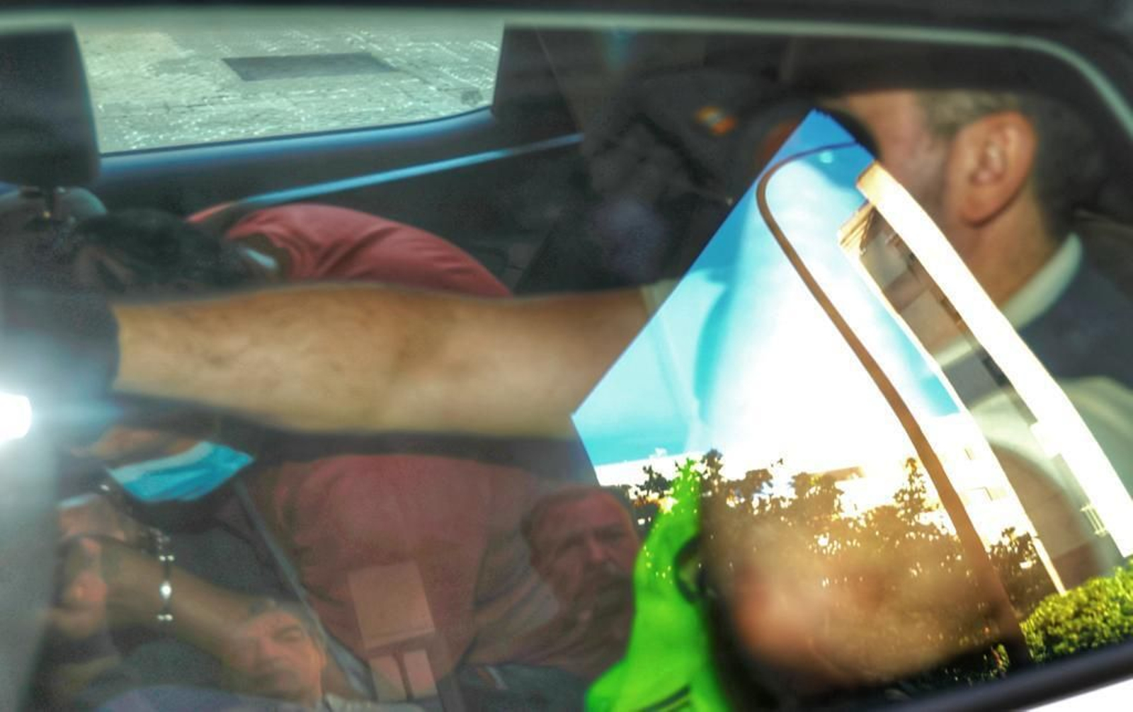 El detenido, con camiseta roja y mascarilla, en el interior del coche camino de los juzgados.