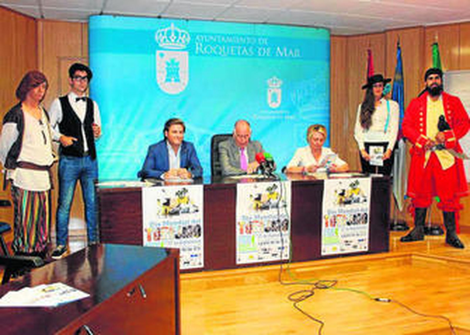 Alcalde y concejales durante la presentación de los actos, acompañados de participantes.