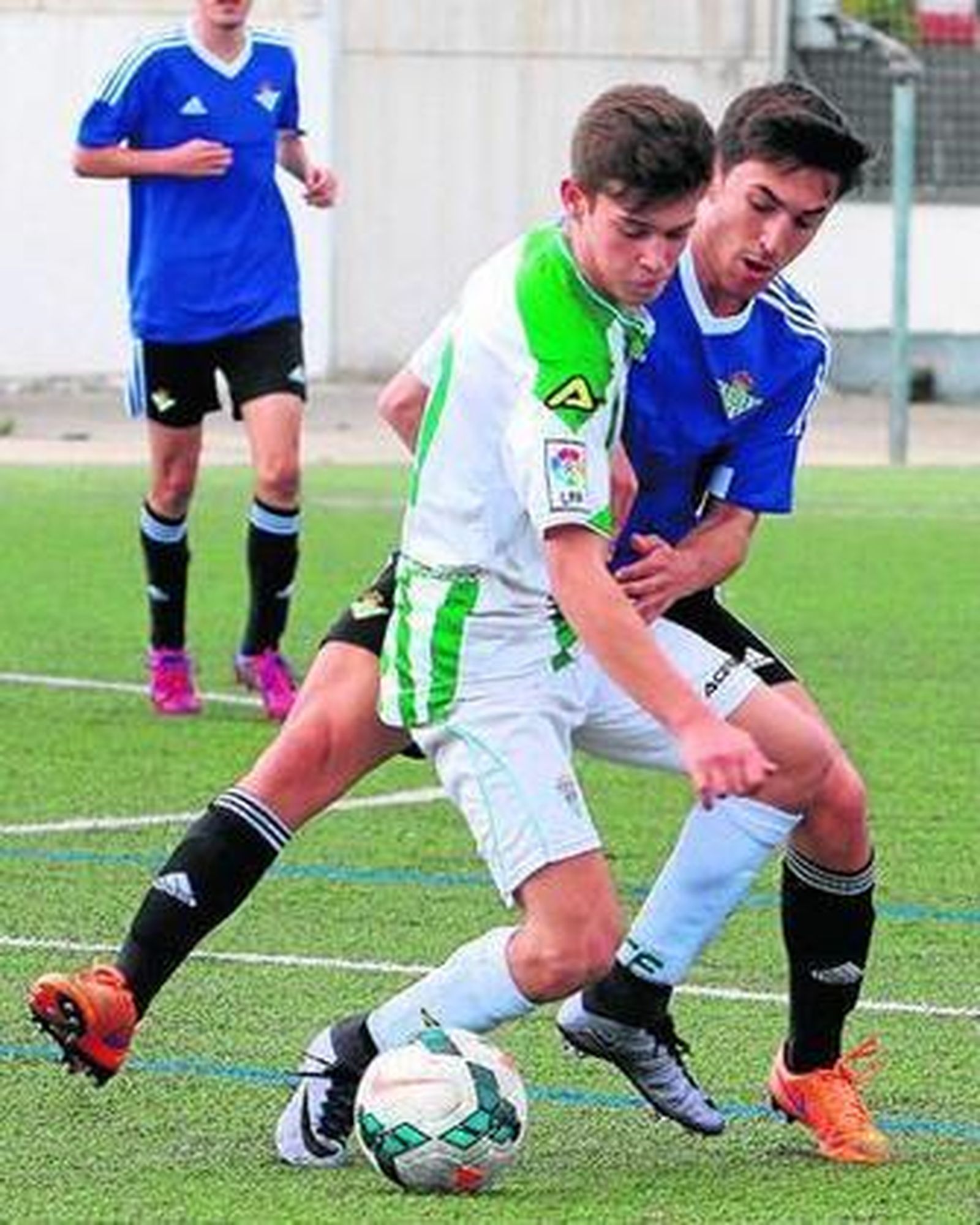 Un jugador blanquiverde protege el balón ante la presión de un bético