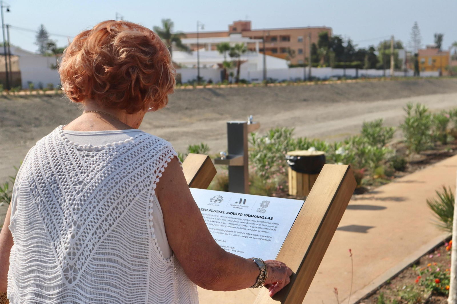 Una mujer observa el cartel de inicio del paseo fluvial en Rincón de la Victoria.