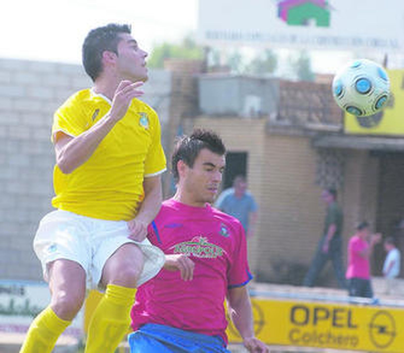 Juan Carlos se eleva por encima de Domi Elías para intentar golpear el balón.