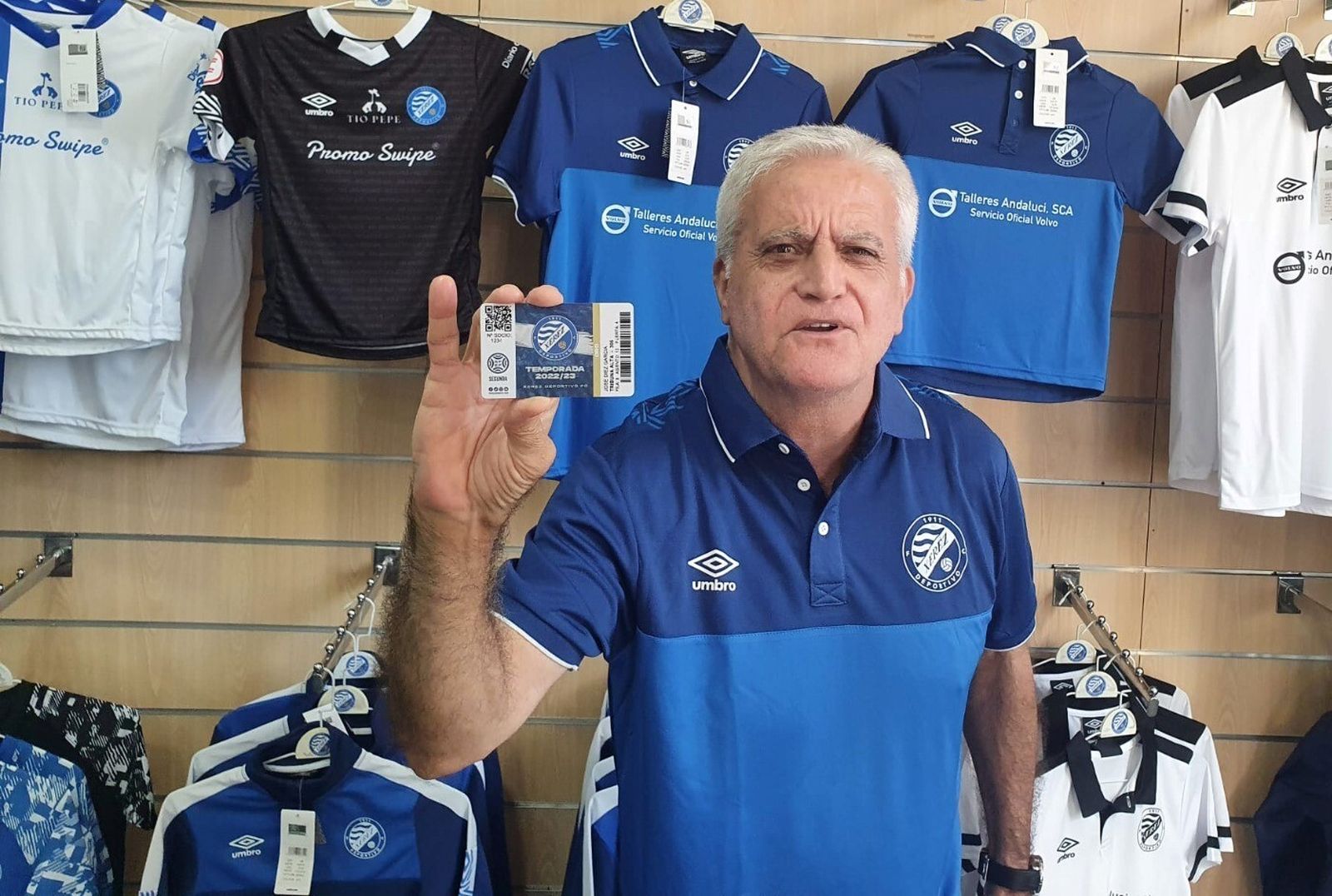 Un aficionado posa con su carné en la oficina del club.