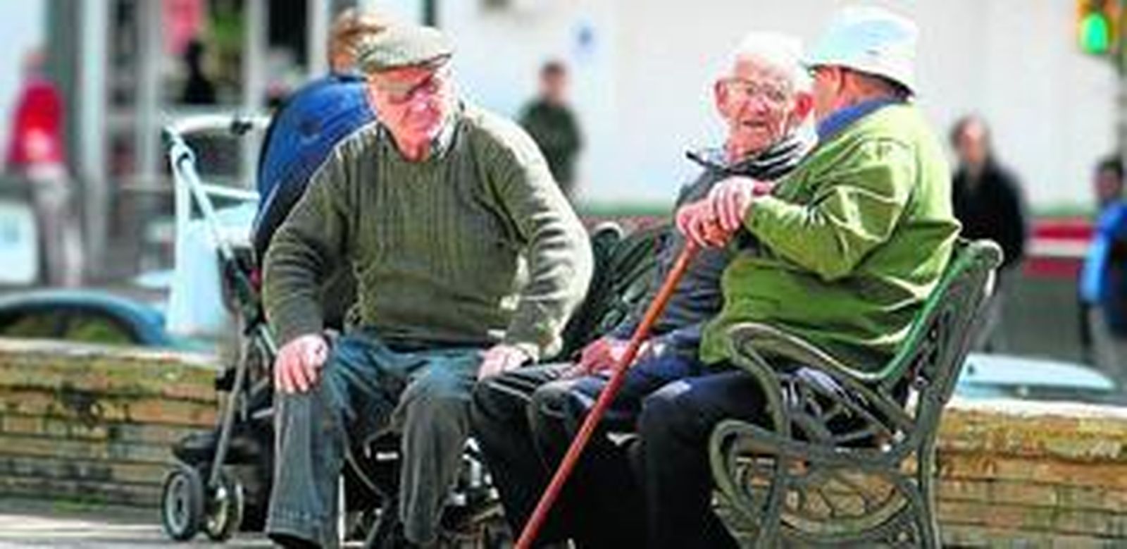 Un grupo de ancianos toman el sol en una plaza de Sevilla.