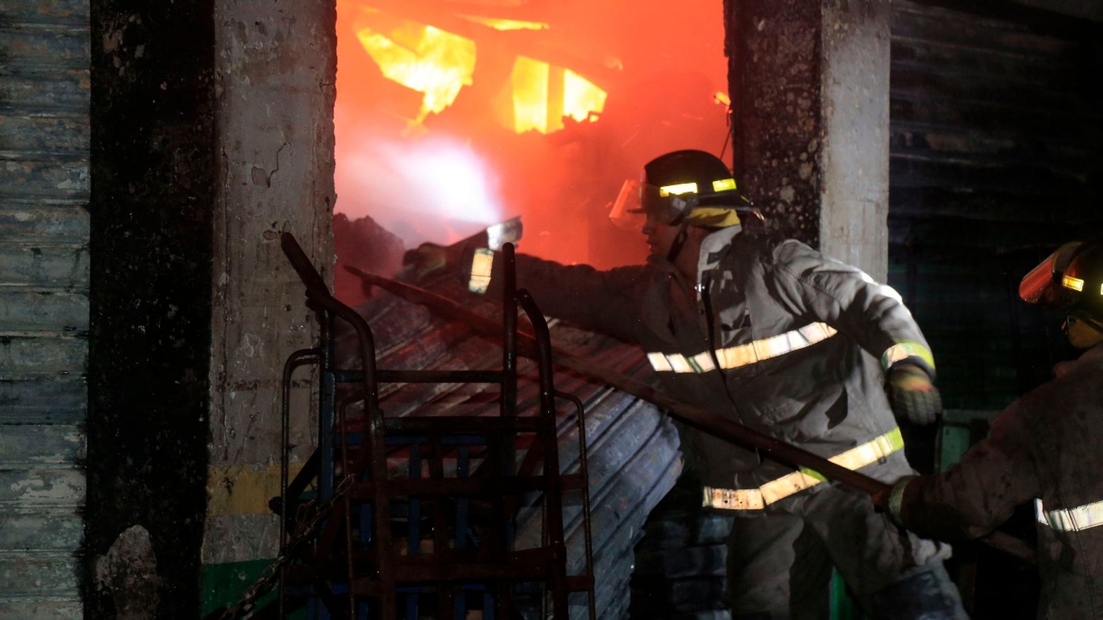 Un integrante del Cuerpo de Bomberos de Honduras trabaja para controlar el fuego durante un incendio en el mercado Medina Concepción de San Pedro Sula.