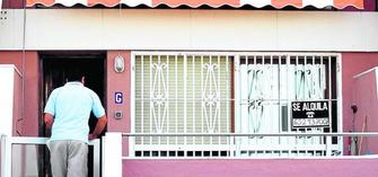 Un hombre entra en una vivienda de primera línea de playa que luce en su ventana una oferta de alquiler.