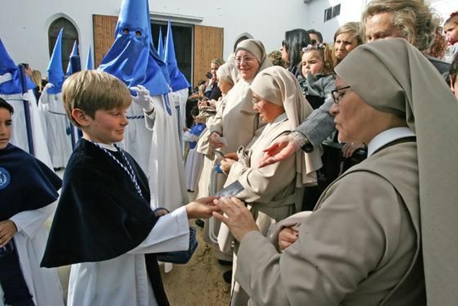 Uno de los monaguillos de La Borriquita ofrece una estampita a una monja a la salida

Foto: Juan Carlos Toro