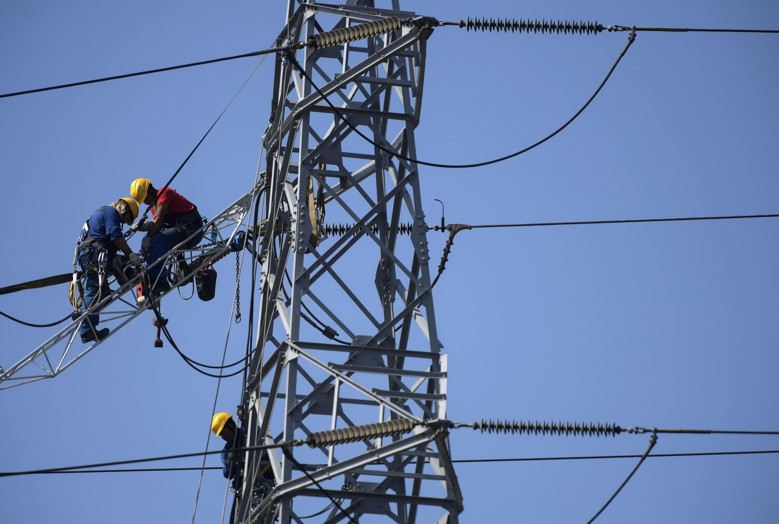 Imagen de archivo de dos operarios trabajando en una línea de alta tensión