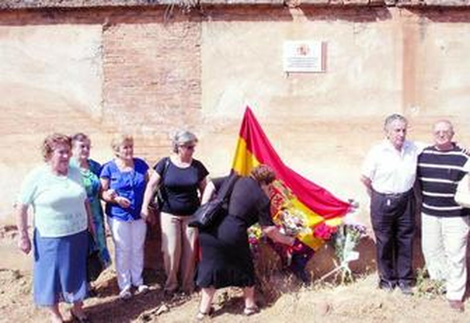 Familiares de fusilados ante la placa de homenaje colocada en la tapia del cementerio.