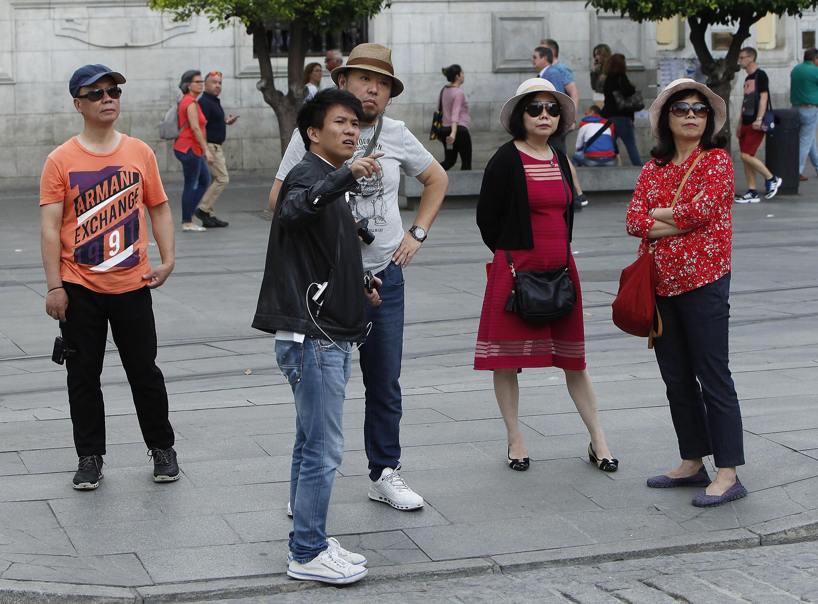 Un grupo de turistas asiáticos atiende a las explicaciones que les proporciona un guía.