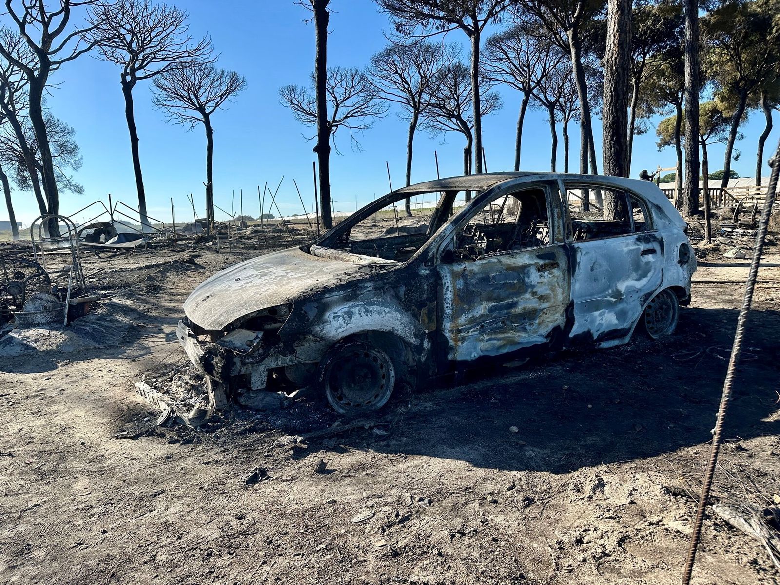 Un coche calcinado en el incendio en el asentamiento chabolista de Lucena del Puerto, el pasado sábado.