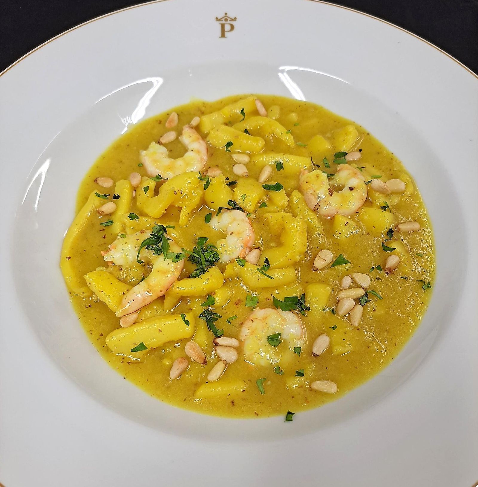 Choco con salsa de azafrán, gambas y piñones. Consiste en un guiso de choco (sepia), previamente emparrillado y terminado en una salsa azafranada con gambas y piñones.