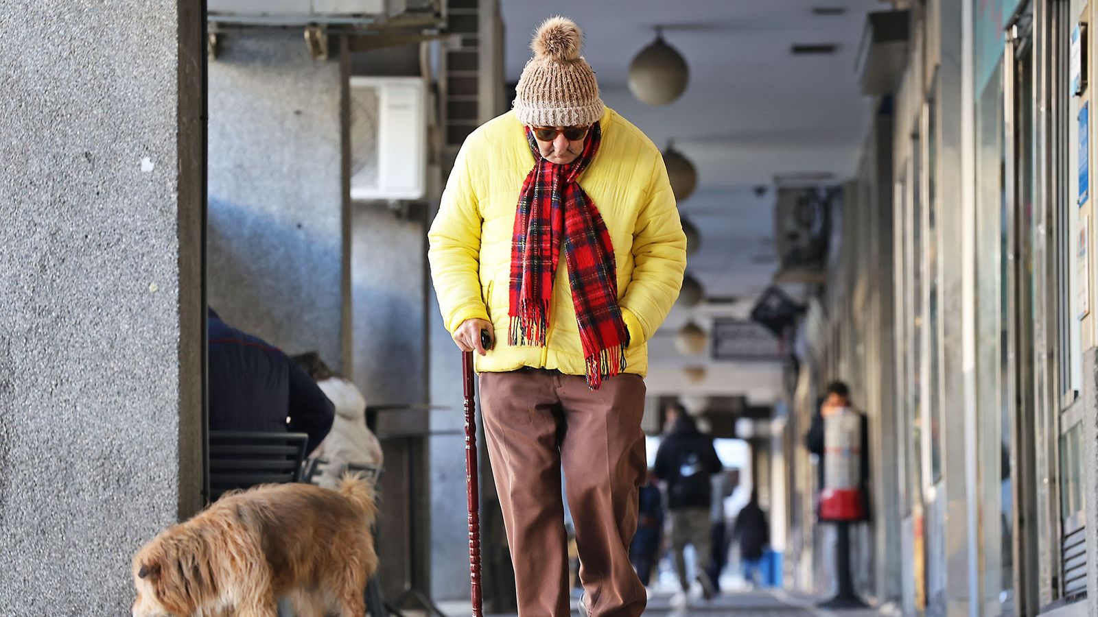 Una persona con gorro y bufanda se refugia del frío de la mañana en Huelva.