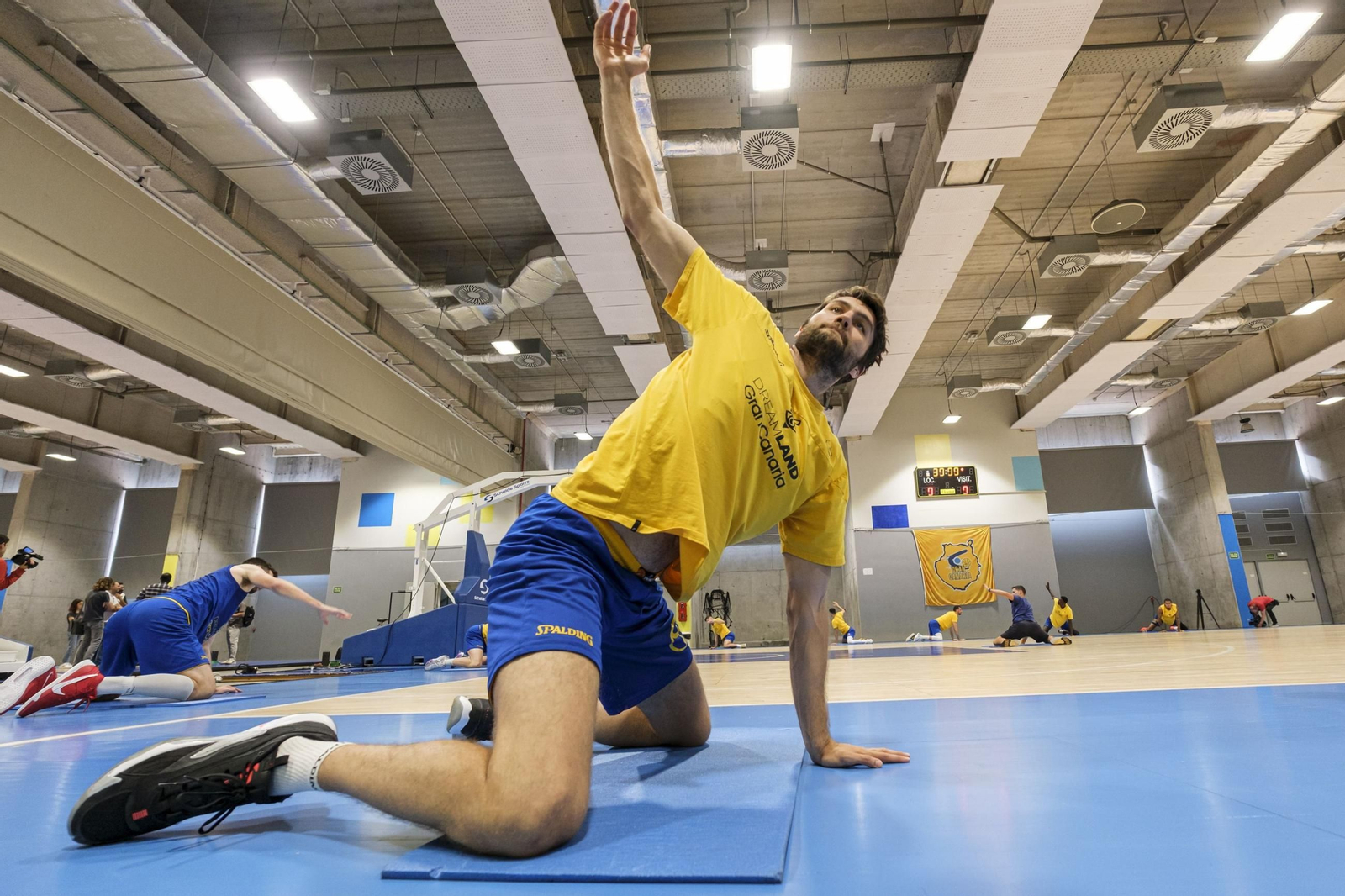 Un deportista realiza estiramientos al término de una sesión de entrenamiento con su equipo.