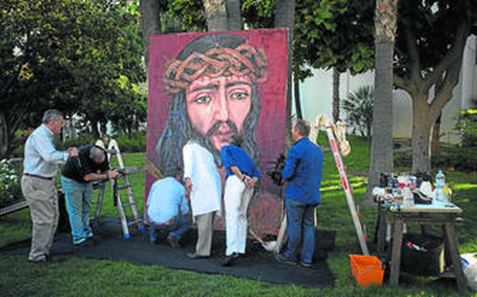 Varias personas  participan, junto al pintor, en la realización del cuadro.
