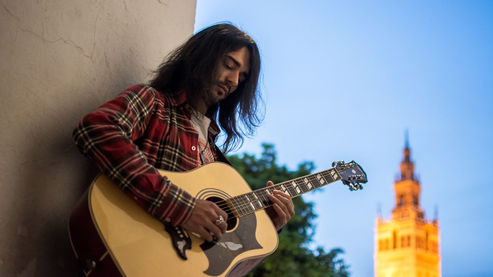 Joey toca su guitarra acústica con la Giralda al fondo