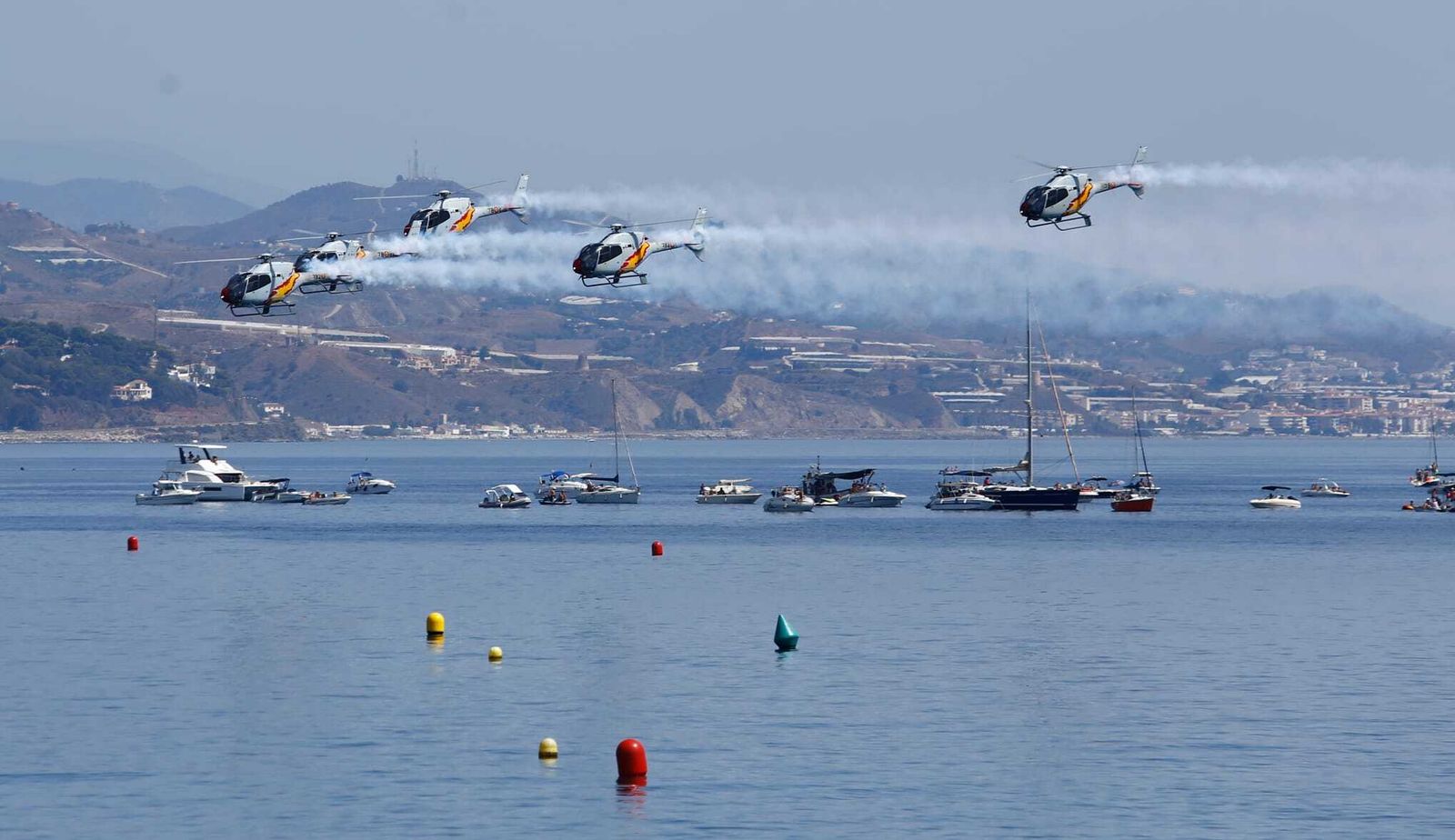 Varios helicópteros en formación dejan estelas de humo durante la exhibición aérea en Torre del Mar, este domingo.