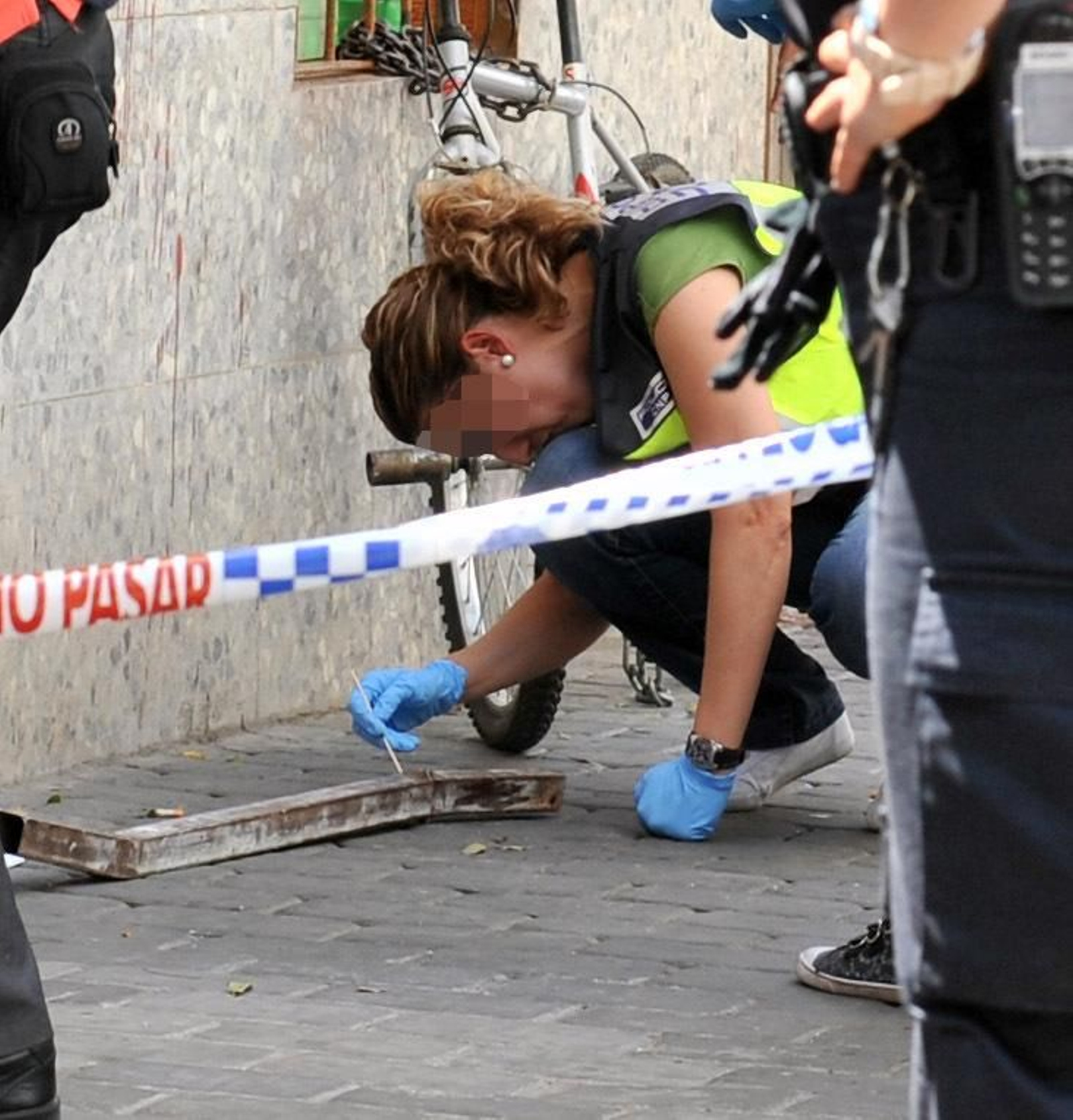 Una agente de la Policía Nacional toma muestras en una barra de hierro.