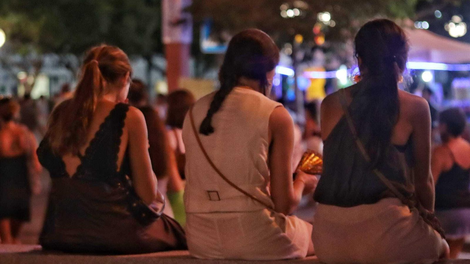 Tres amigas descansan los pies antes de continuar la marcha en el recinto ferial.